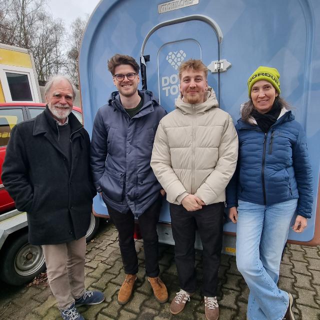 Vier Personen von Downtown Delights und KIDS Hamburg e. V. stehen bei der Übergabe nebeneinander vor dem Wagen